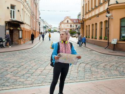 kvindelig ung turist står med et kort i en fremmed by