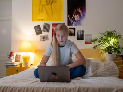 Teenagepige i seng med computer