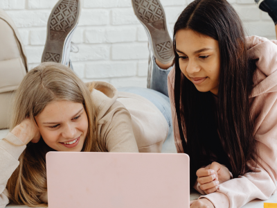 2 tweens/piger kigger på en skærm og griner